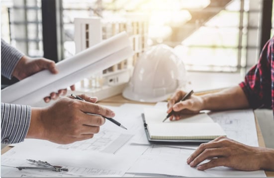 Hände zweier Ingenieure über Bauzeichnungen